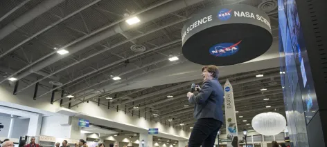 A speaker addresses a crowd in a NASA Hyperwall talk at the American Geophysical Union annual conference.