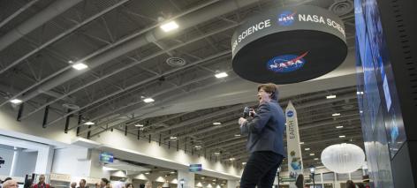 A speaker addresses a crowd in a NASA Hyperwall talk at the American Geophysical Union annual conference.
